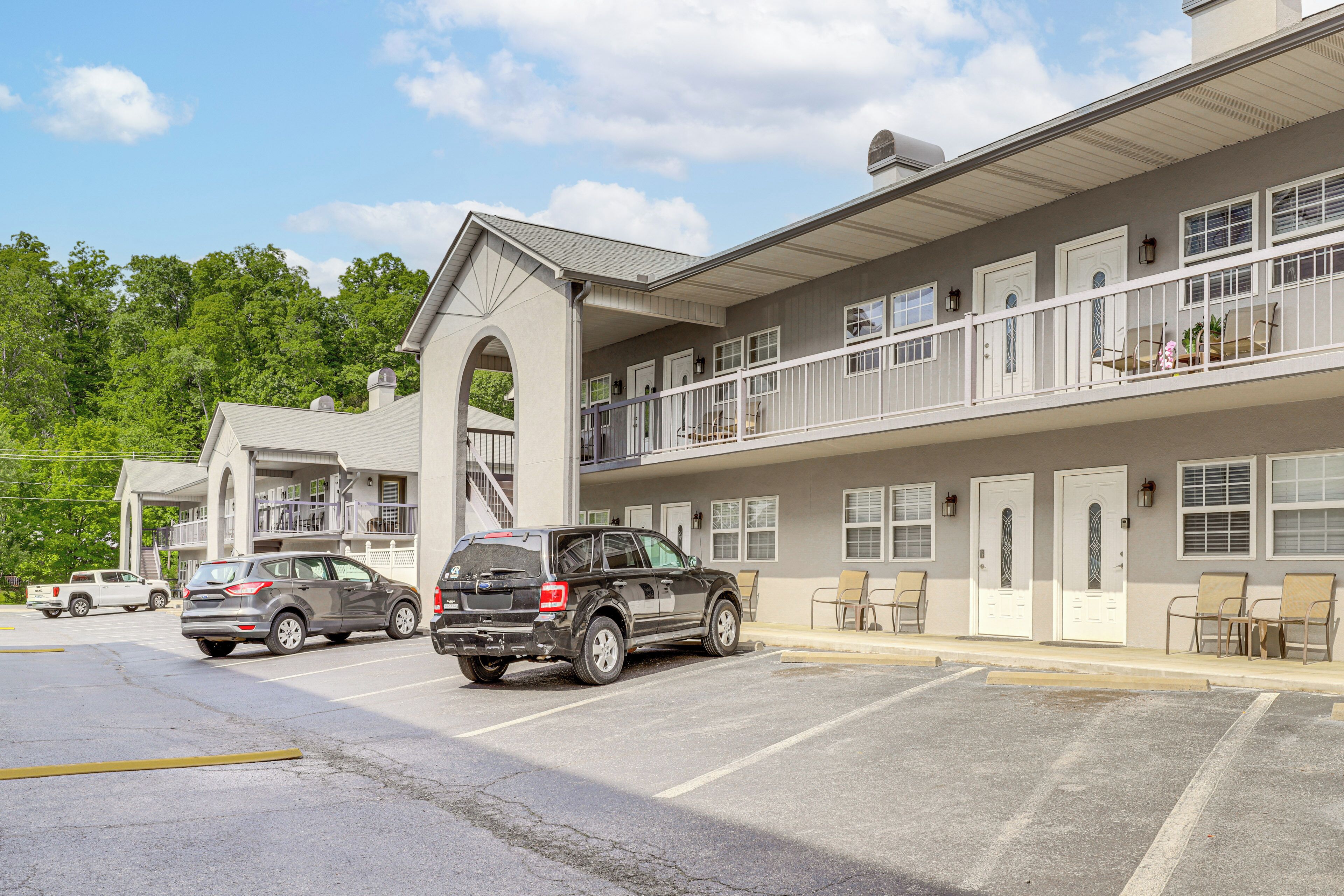 Un bâtiment à deux étages doté d’un parking, d’un espace extérieur abrité avec des sièges et d’un escalier menant à un niveau supérieur.