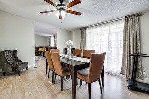 A dining area with a wooden table, chairs, a ceiling fan, and a treadmill.