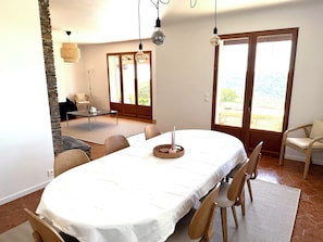 Un comedor con una mesa, sillas, un candelabro y vistas a través de un ventanal.