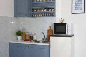 Une cuisine équipée d’un four à micro-ondes, d’un évier, de placards bleus et d’un porte-épices.