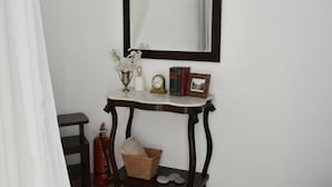 Een kamer met een donkerhouten console tafel, een witte vaas met bloemen, een klok, boeken en een ingelijst fotokader.