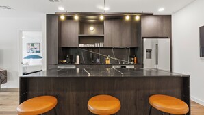 A modern kitchen with a central island, bar stools, and built-in appliances.