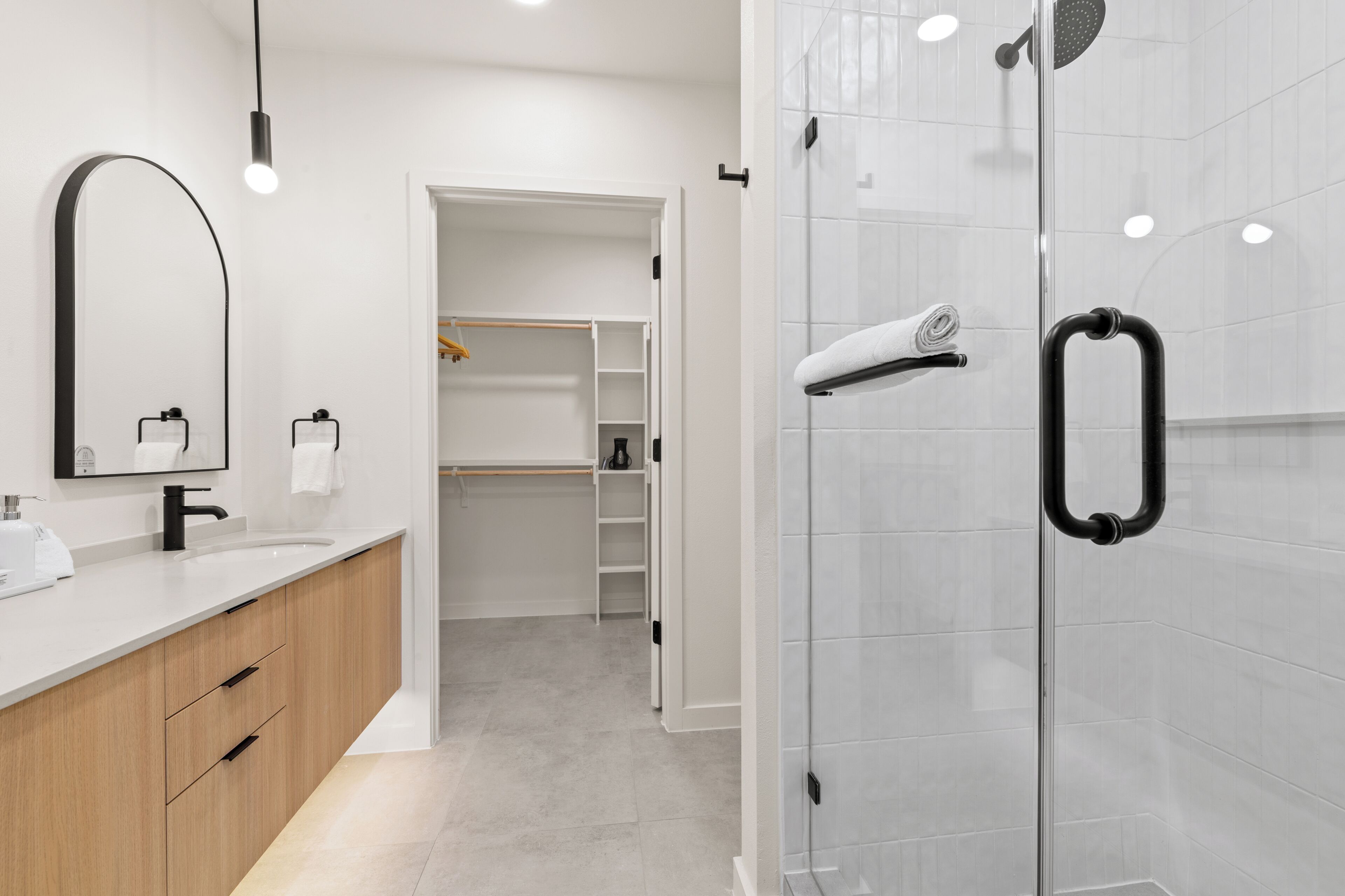 Ein modernes Badezimmer mit Duschkabine aus Glas, einem weißen Waschbecken und einem Holz-Badmöbel.