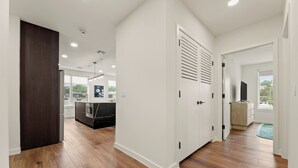 A modern kitchen with wooden flooring, white walls, and a dark wood door.