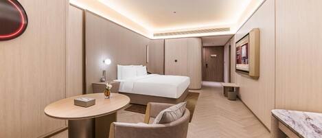 Habitació d'hotel moderna amb llit, taulella de nit, cadira i una taula petita amb làmpada.