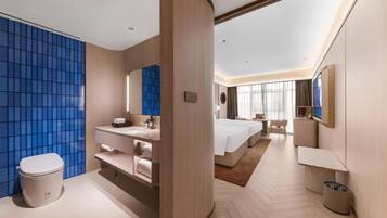 Una habitación de hotel moderna con una cama grande, baño independiente, escritorio y ventana amplia.