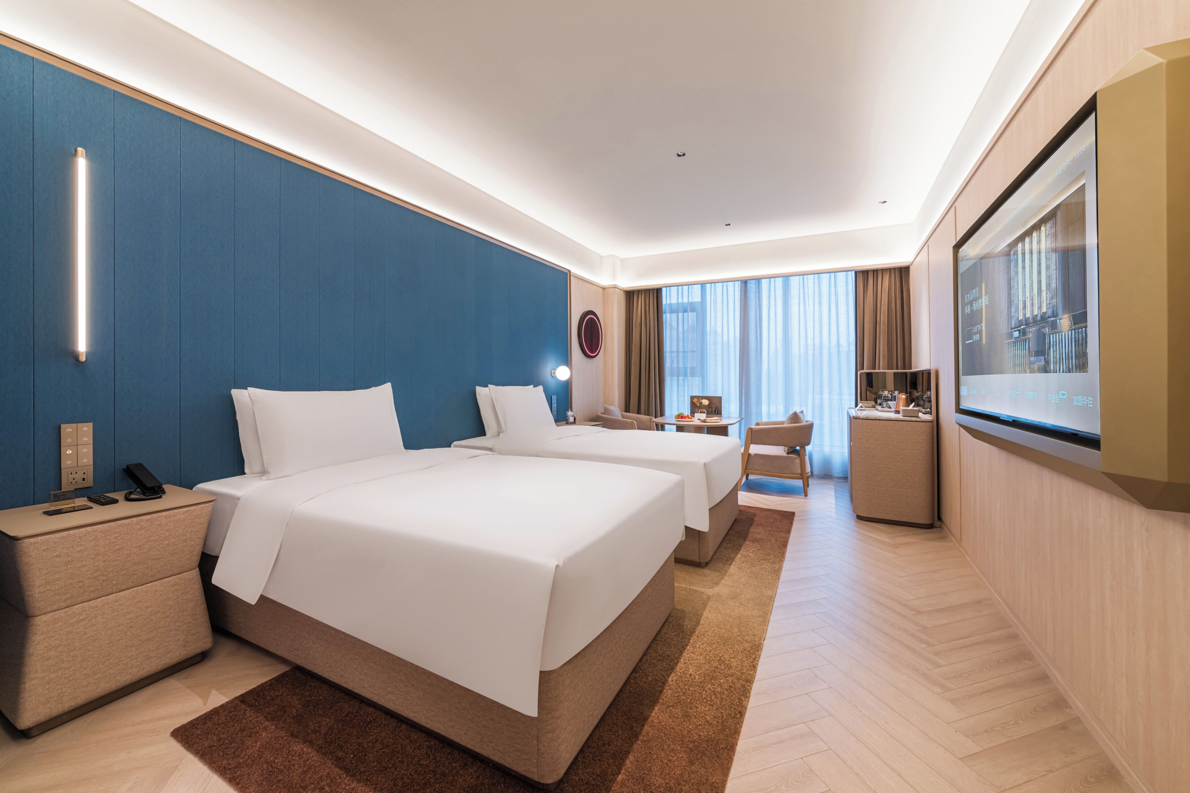 Habitación de hotel con dos camas, un escritorio, una silla, un televisor y un minibar.