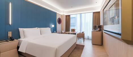 A hotel room with a large bed, bedside table, lamp, and a TV on the wall.