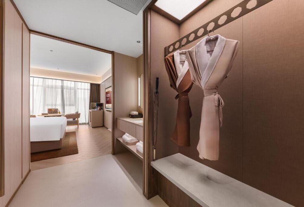 Una habitación de hotel con cama, baño con espejo y una bata colgada en la pared.
