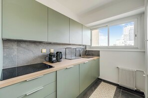 Eine moderne Küche mit Einbauherd, Kaffeemaschine und einem Fenster mit Blick auf die Stadt.