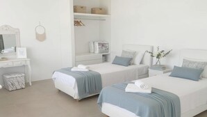 Une chambre d’hôtel avec deux lits, une coiffeuse avec un miroir et une armoire avec des paniers.