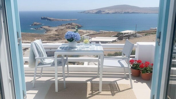 Un balcon avec une table, des chaises, un vase de fleurs et des plantes en pot.