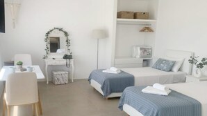 Une chambre d’hôtel avec deux lits, un bureau, une chaise, une armoire et un miroir orné d’une guirlande verte.