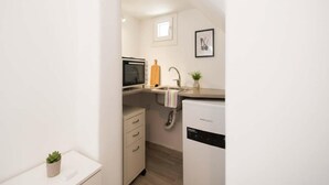 Cocina compacta con microondas, lavamanos y un refrigerador pequeño.