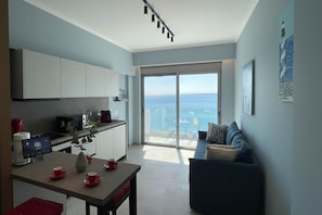Eine moderne Küche mit Essbereich, eine große Schiebetür zu einem Balkon und Blick auf das Meer.