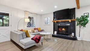 Una sala de estar con chimenea, sofá y televisor.