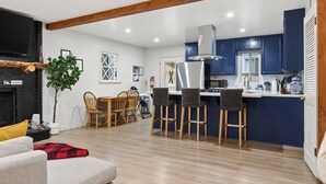 Una cocina moderna con armarios azules, taburetes de madera y una mesa de comedor con sillas.