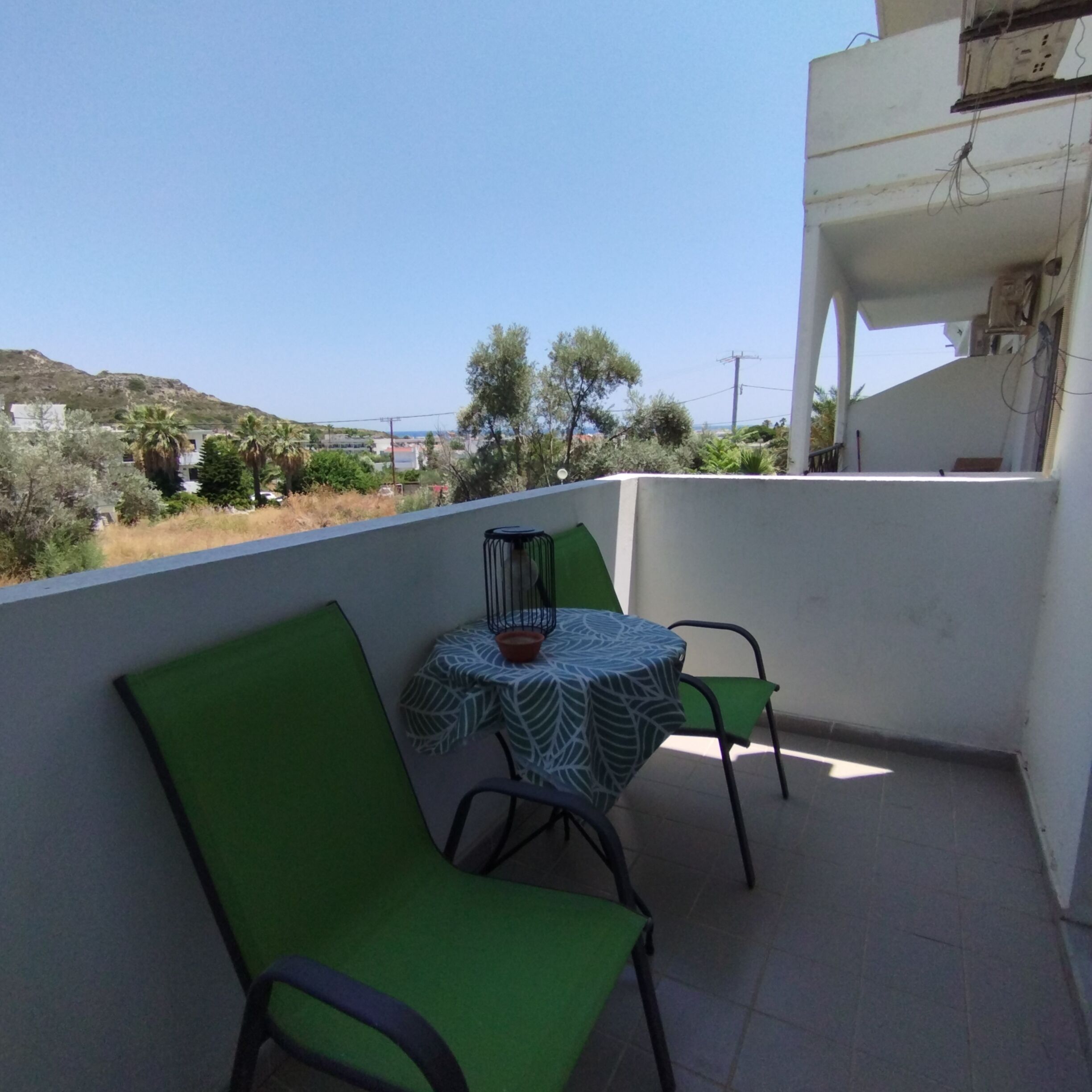 Un balcon avec une table et des chaises, une vue sur le paysage et un bâtiment en arrière-plan.