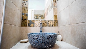 Une salle de bain avec un lavabo en mosaïque, un miroir et des carreaux à motifs.