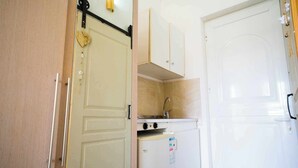 Une cuisine de taille réduite, équipée d’un évier, d’un petit réfrigérateur et de placards peu encombrants.