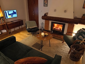 Ein Wohnzimmer mit Kamin, einer Couch, einem Couchtisch und einem Fernseher.