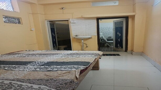A bedroom with a bed, a sink, and a door leading to another room. - Sabitri Homestay (Puri)