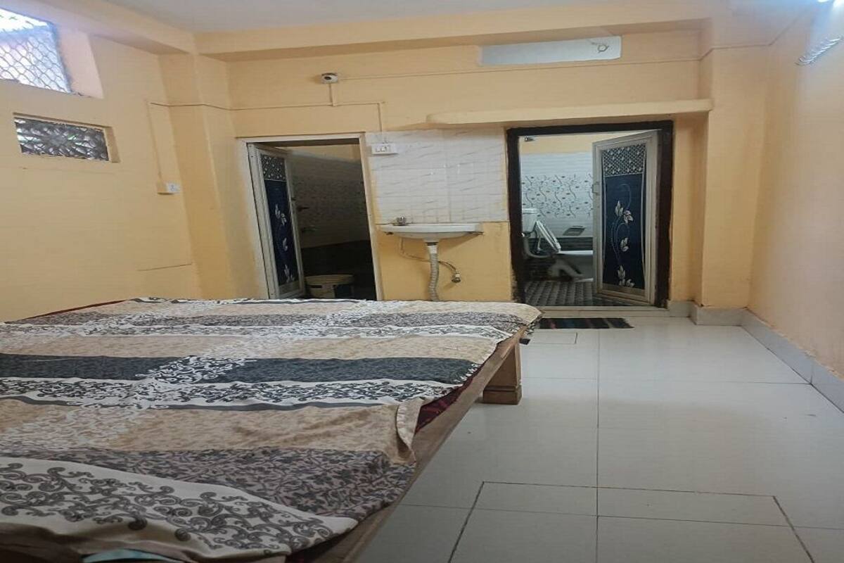 A bedroom with a bed, a sink, and a door leading to another room.