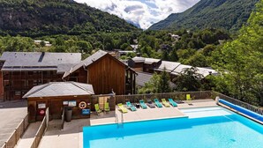 A pool area with lounge chairs, a wooden building, and a mountainous backdrop. - Apartment for 4 near the Gondola (Ax-les-Thermes)