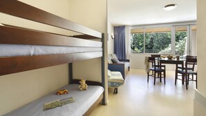 A room with a bunk bed, a dining table with chairs, and a view through a window. - Studio in the Heart of Nature (Vallon-Pont-d’Arc)