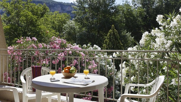 A balcony with a table, chairs, and a view of trees and mountains. - Studio in the Heart of Nature (Vallon-Pont-d’Arc)