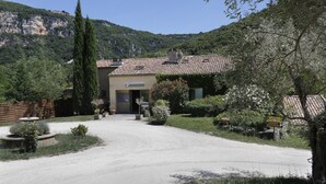 A building with a tiled roof, a gravel driveway, and a sign indicating a restaurant. - Studio in the Heart of Nature (Vallon-Pont-d’Arc)