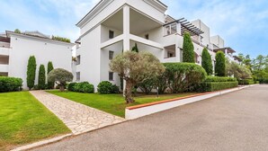 A modern building with a clean, white facade, a central courtyard, and neatly trimmed hedges.