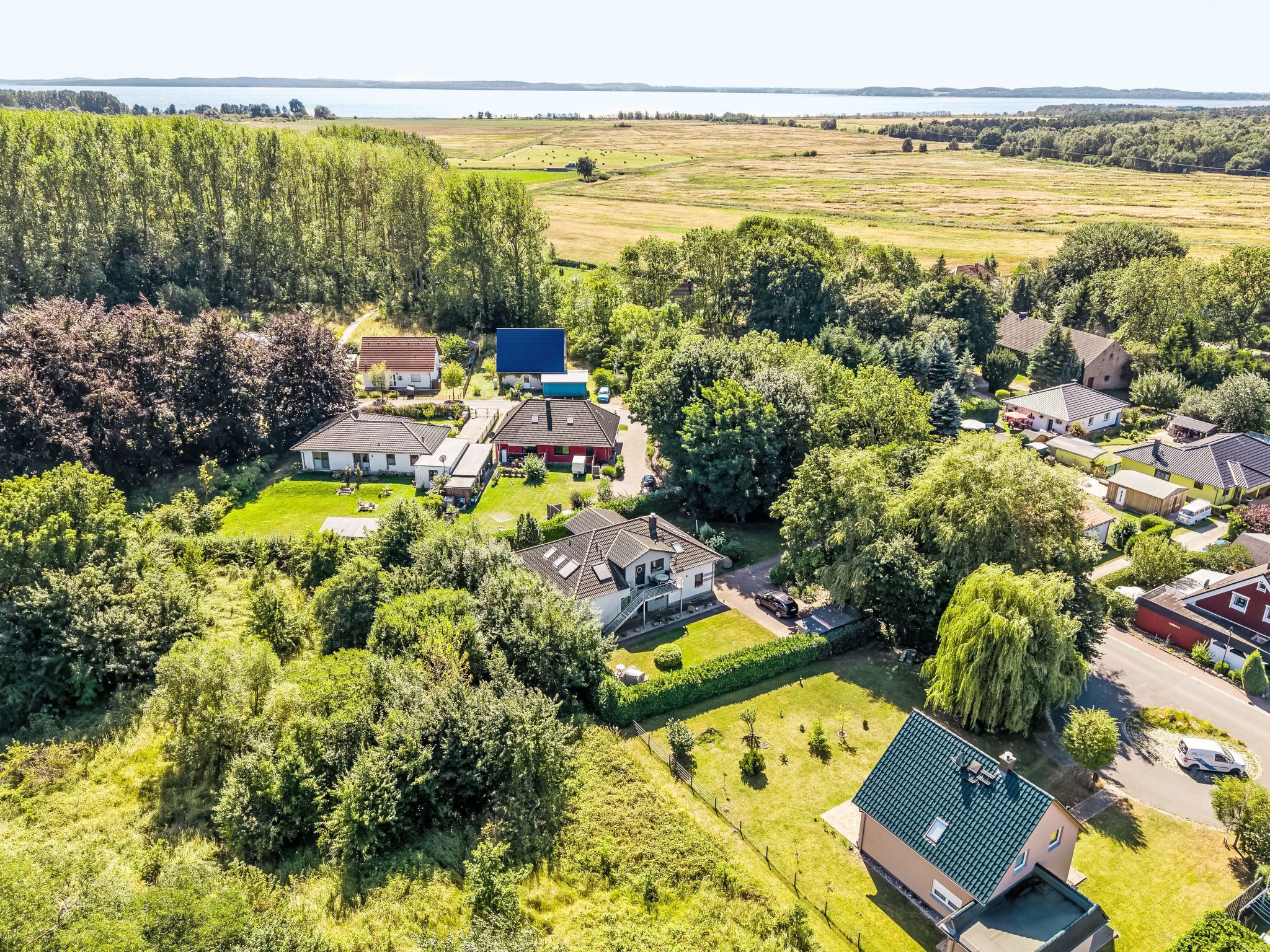 An aerial view of a residential area with houses, green spaces, and a lake in the background.