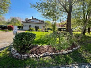 Ein Haus mit Ziegeldach, umgeben von einem gepflegten Rasen und einer Steingrenze.