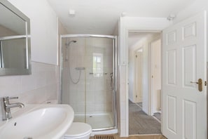 A bathroom with a glass shower enclosure, a sink, and a toilet.
