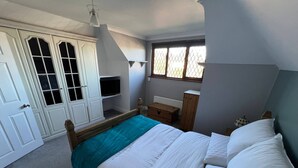 Een slaapkamer met een bed, een kaptafel, een raam en een kledingkast.