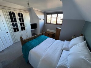 Ein Schlafzimmer mit einem Bett, einem Schminktisch, einem Fenster und einem Kleiderschrank.