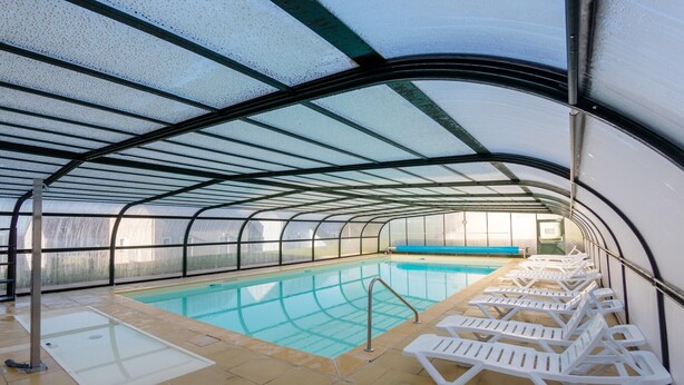 A covered swimming pool with clear water, surrounded by white lounge chairs and a tiled floor. - Brittany Flat near Pentrez Beach (St Nic)