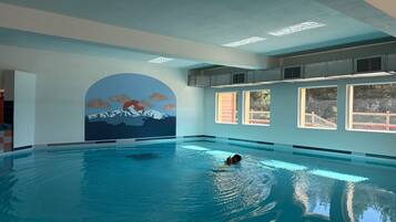 Una piscina interior con un mural de un paisaje montañoso en la pared.