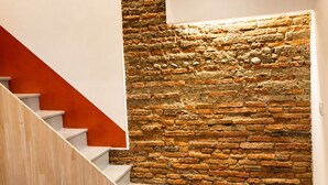 Una escalera moderna con barandilla de madera y pared de piedra.