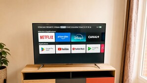 Un televisor sobre un soporte de madera con varias aplicaciones de transmisión visibles.