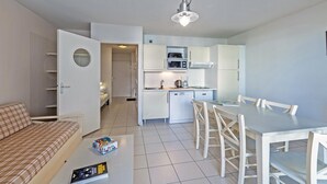 A compact living space with a kitchenette, a dining area, and a sofa. - Stay with Indoor Pool & Sea (Plougonvelin)