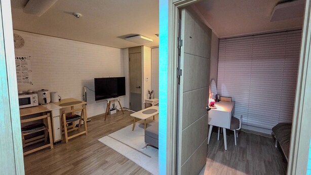 Ett modernt vardagsrum med en platt-TV, möbler i trä, en vit soffa och ett litet skrivbord med en lampa.