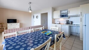Een knus verblijf met een eettafel, stoelen, een televisie, een kitchenette en een badkamedeur.