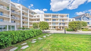 Een hotel met meerdere verdiepingen, met balkons, een gazon en een helderblauwe lucht.