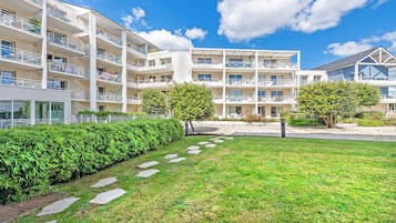 A multi-story hotel with balconies, a grassy courtyard, and a clear blue sky.