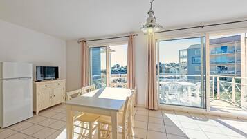 A modern apartment with a kitchen, dining area, and large balcony with a view.