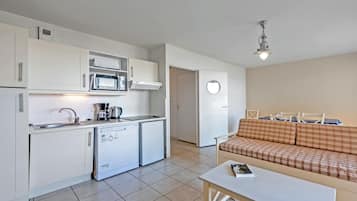 A compact kitchen with a microwave, coffee maker, and a small refrigerator.