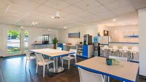Un restaurante moderno con decoración en blanco y azul, una zona de cocina y vistas al exterior.