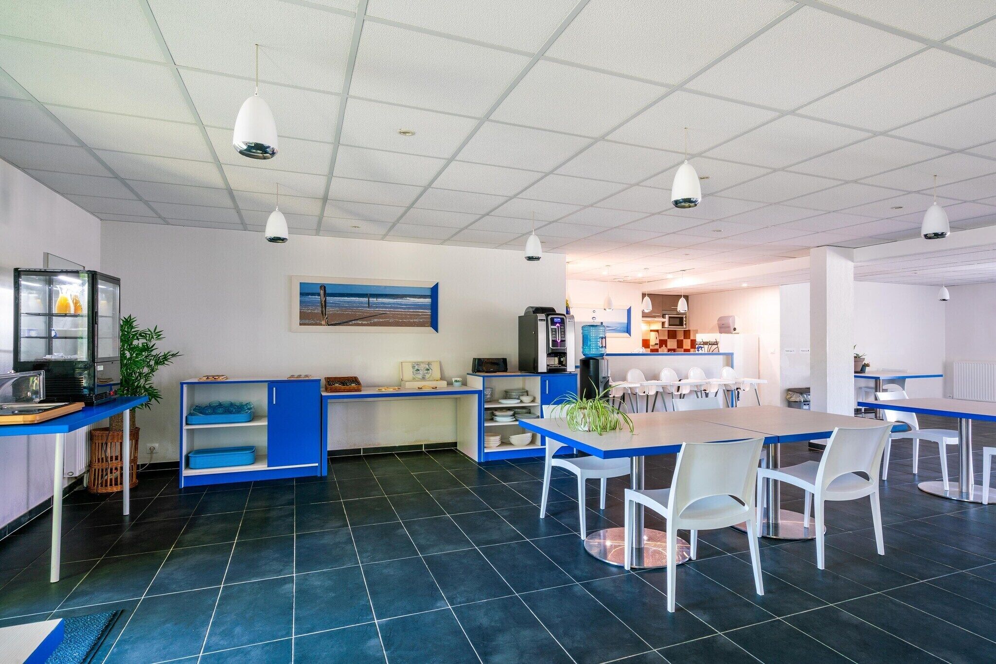 Una cocina moderna con comedor, que incluye una isla grande, sillas blancas e iluminación colgante.